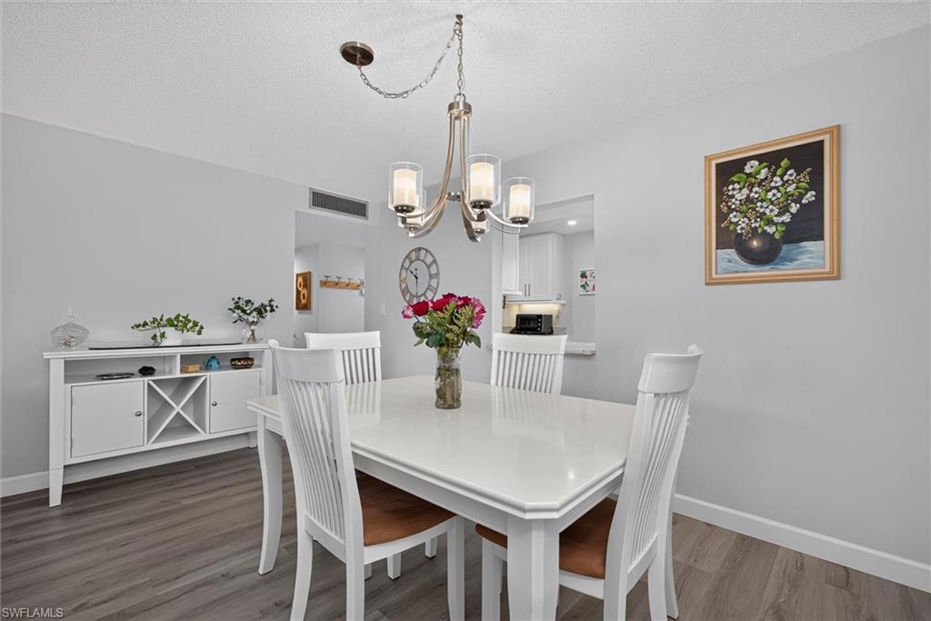 Dining area featuring wood-finish flooring, a contemporary chandelier, a built-in buffet with wine storage, and a pass-through opening