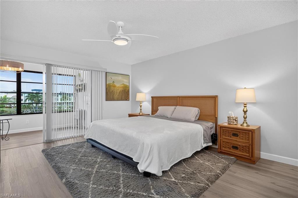 Spacious Master Bedroom interior featuring wood-finish flooring, a contemporary ceiling fan with integrated lighting, and a broad sliding glass door