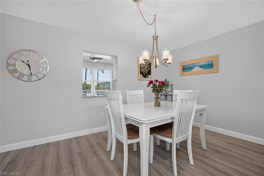 Dining area featuring wood-finish flooring, a contemporary chandelier, and a pass-through window