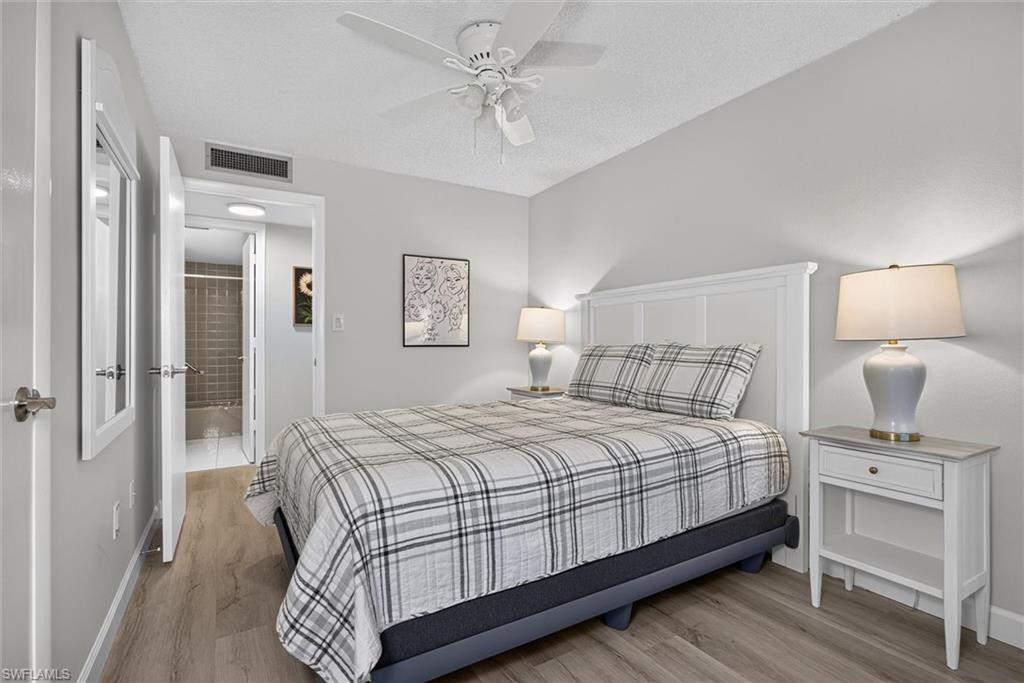 Guest Bedroom featuring wood-finish flooring, a white paneled headboard, and light gray painted walls