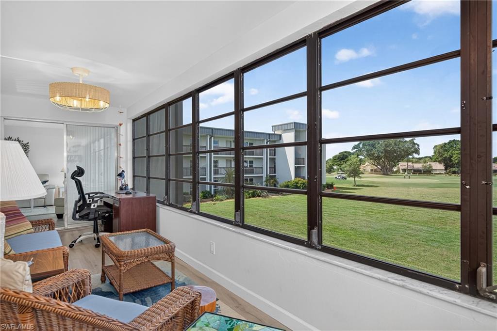 Enclosed Lanai featuring a wall of expansive windows with dark framing, light wood-finish flooring, and a modern ceiling fixture