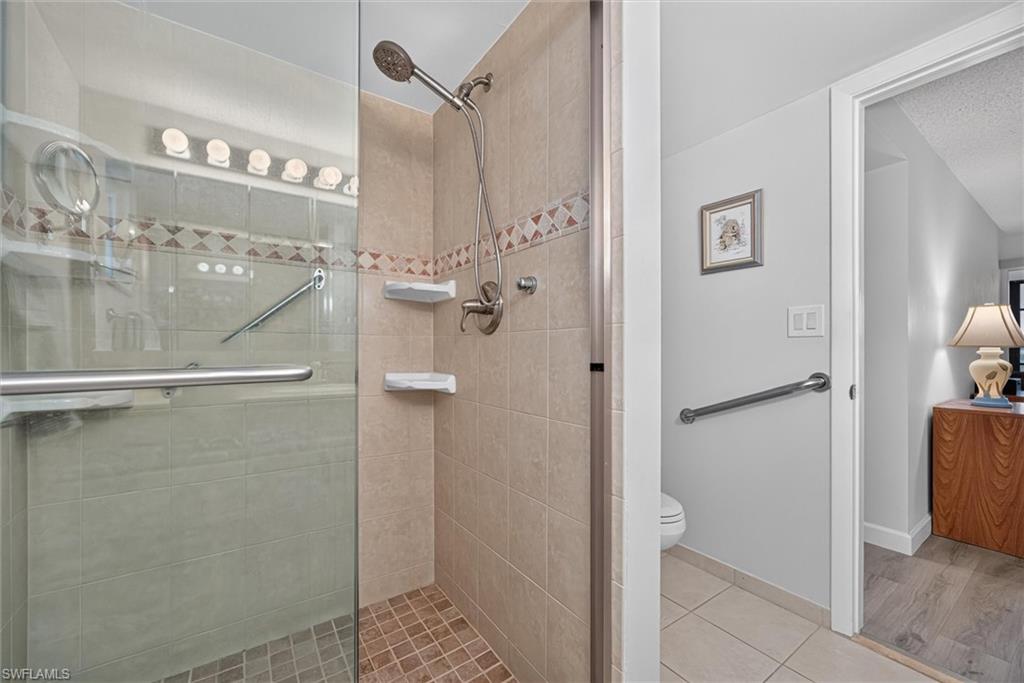 Master Bathroom Tiled shower enclosure featuring a glass door, handheld shower, and integrated shelving