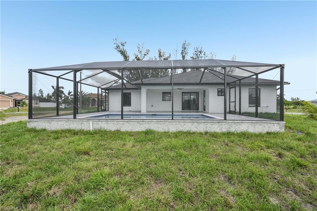 Screened pool enclosure with a rectangular swimming pool, concrete pool deck, and a stucco exterior