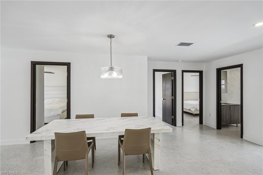 Open living area with a contemporary chandelier, light-toned flooring, and dark wood-finish door frames