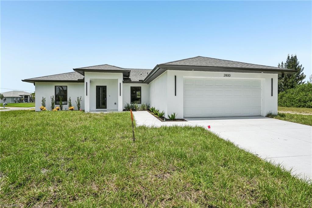 Contemporary single-story exterior with a white stucco finish, dark framed windows, a covered entry, an attached garage, and a concrete driveway