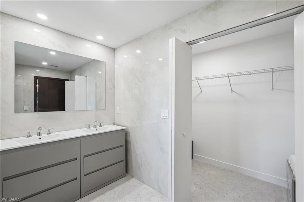 Bathroom featuring a dual vanity with gray cabinetry and integrated sinks, a large wall-mounted mirror, and recessed lighting