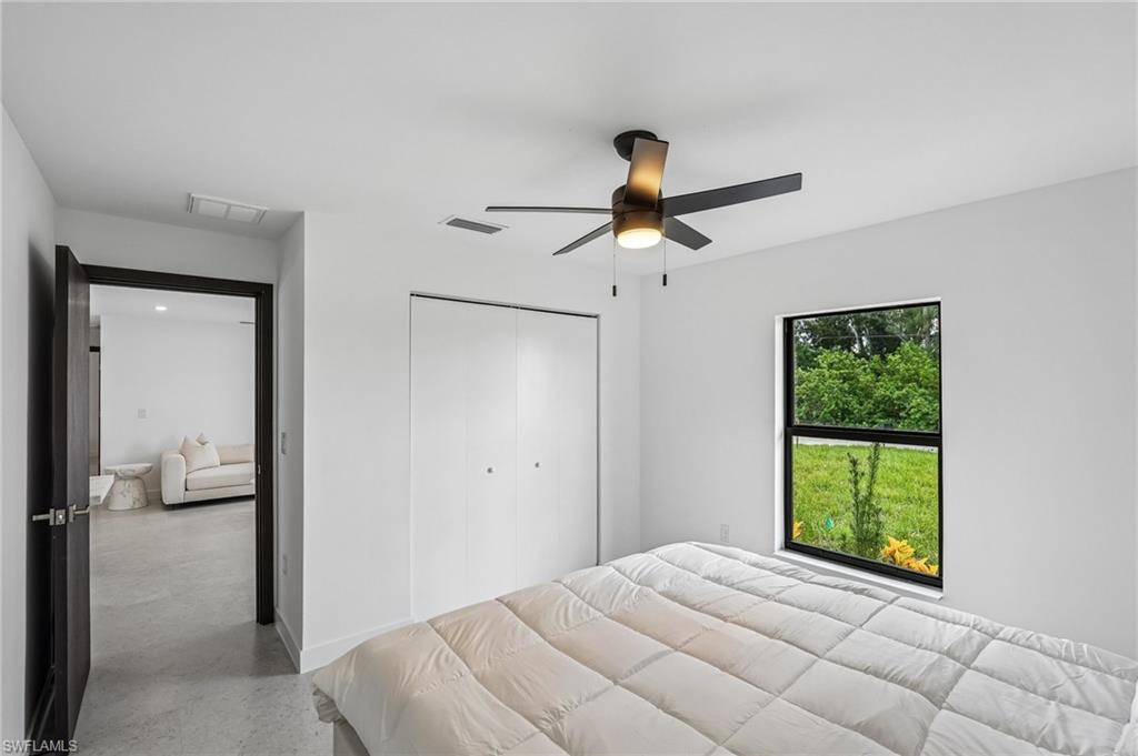 Room featuring a matte black ceiling fan with integrated lighting, a large window with a dark frame, and white bifold closet doors