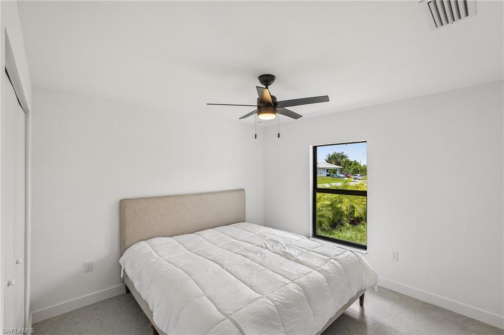 Bright interior space featuring a ceiling fan with integrated lighting, a large window with black trim, and light-toned flooring