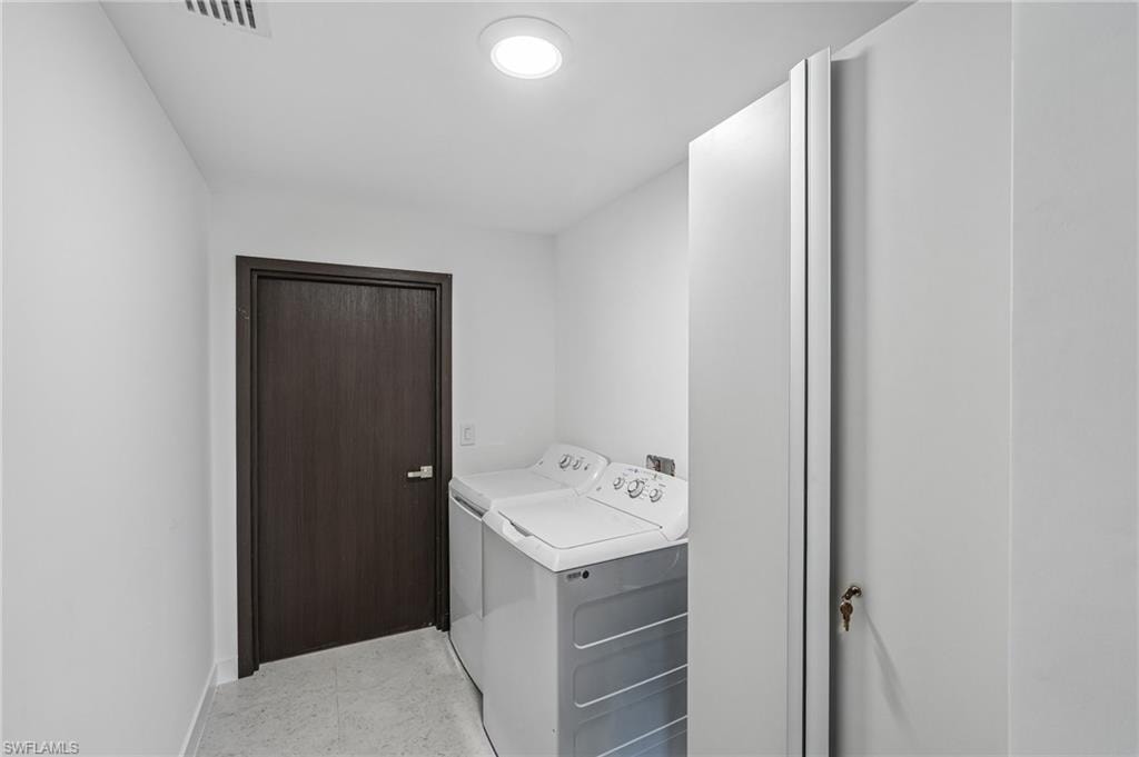 Laundry area featuring a dark wood-finish door, light gray flooring, recessed overhead lighting, and built-in white cabinetry