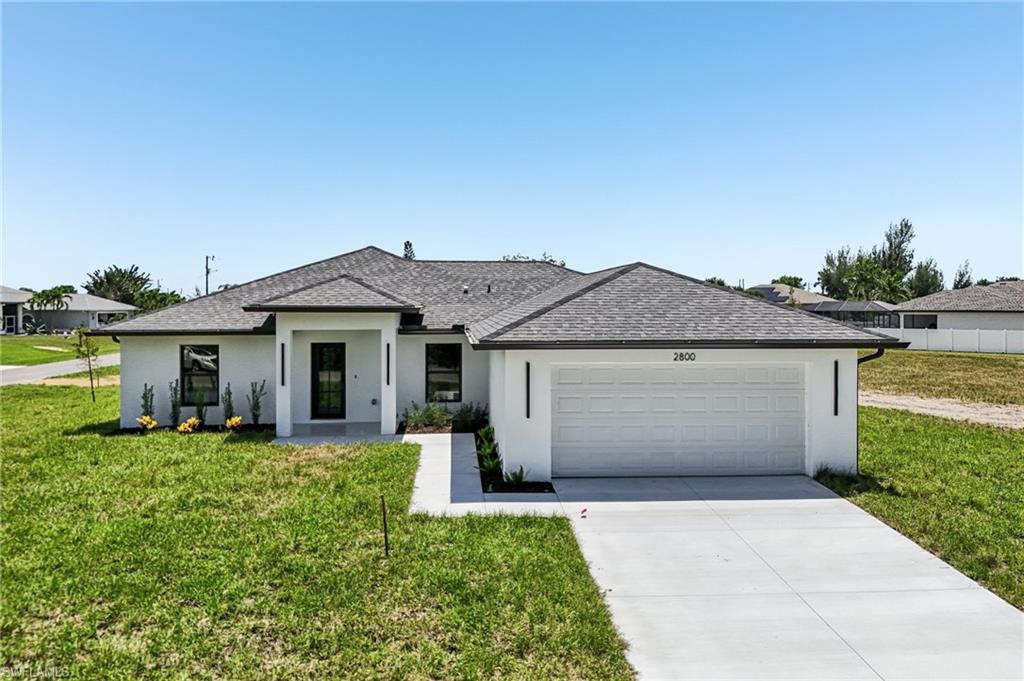 Modern stucco exterior with dark trim accents, a prominent front entry, a two-car garage, and a concrete driveway