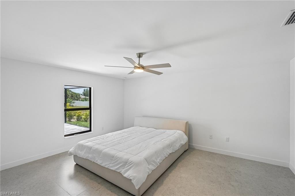 Spacious room featuring a contemporary ceiling fan with integrated lighting, a large window with black framing, durable concrete flooring, and crisp white walls