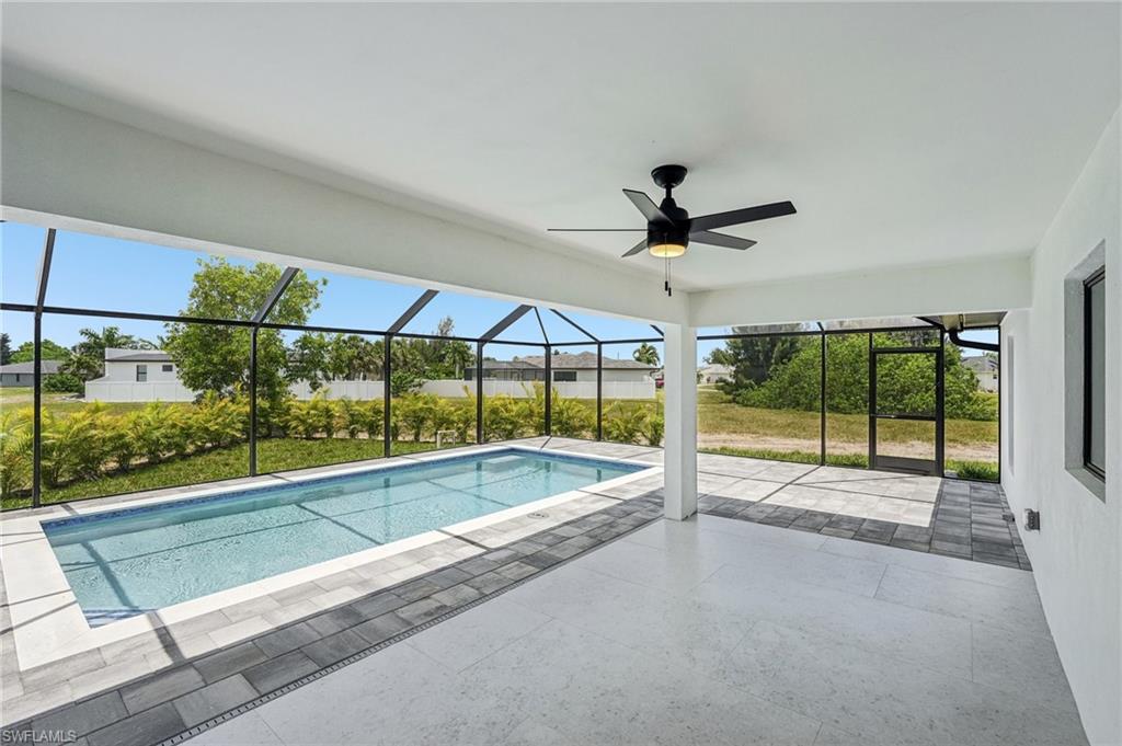 Screened lanai featuring a rectangular swimming pool, integrated ceiling fan, and mixed paver and tile flooring