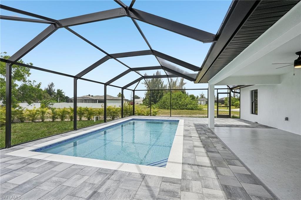 Screen-enclosed swimming pool featuring a light blue tiled interior and a white coping