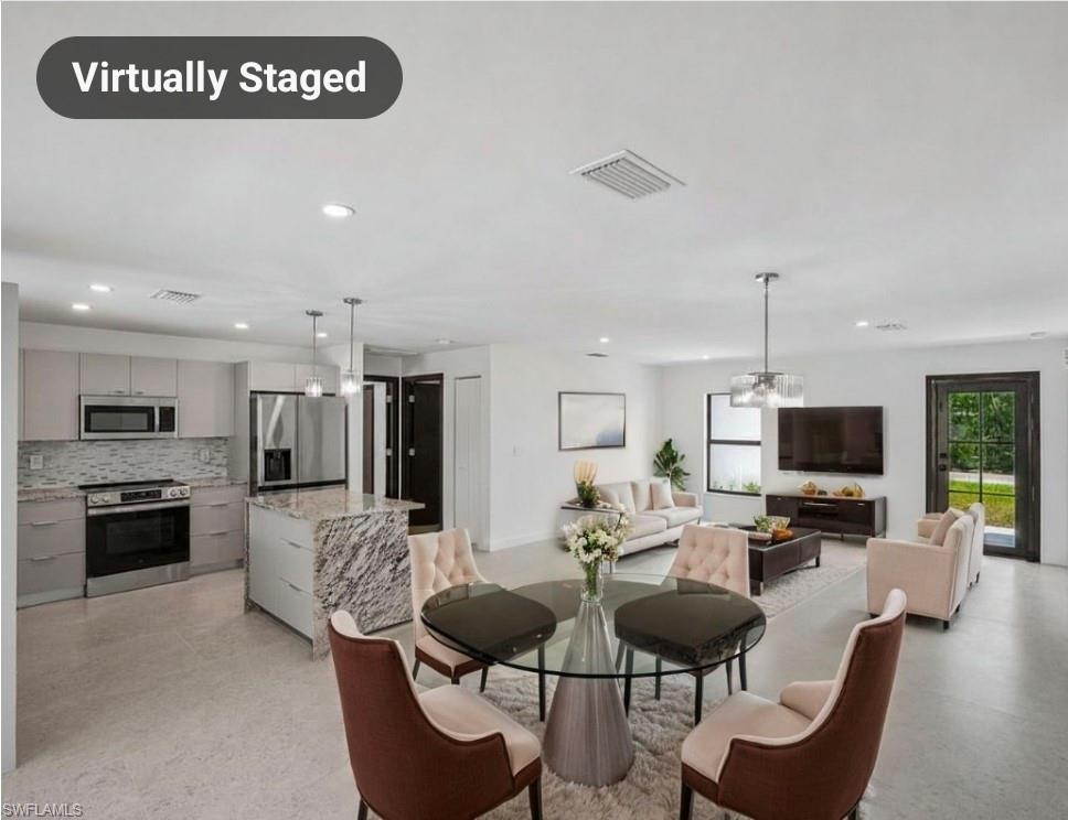 Open-concept living area featuring a modern kitchen with stainless steel appliances, a center island with a stone countertop, recessed lighting, and a glass-paneled exterior door