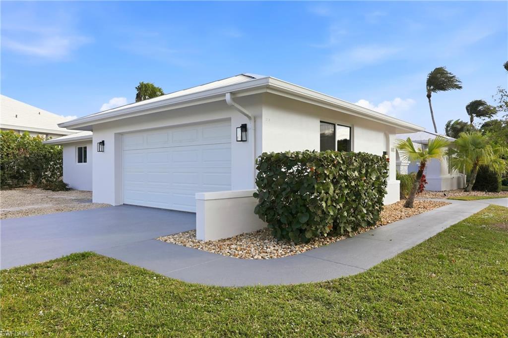View of side of property with concrete driveway, stucco siding, an attached garage, and a yard