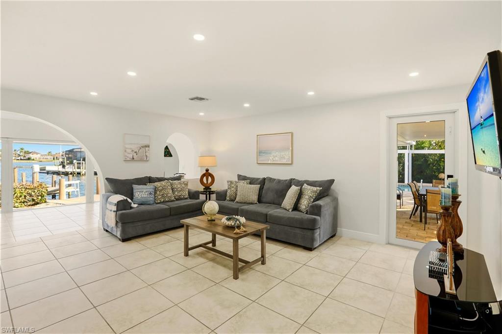 Living area featuring a water view, recessed lighting, light tile patterned floors, and arched walkways