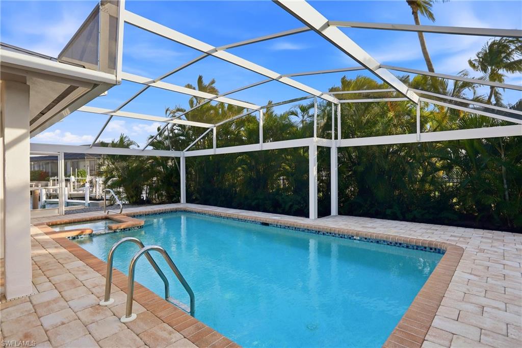 View of pool featuring a sunroom, a patio, glass enclosure, and a pool with connected hot tub