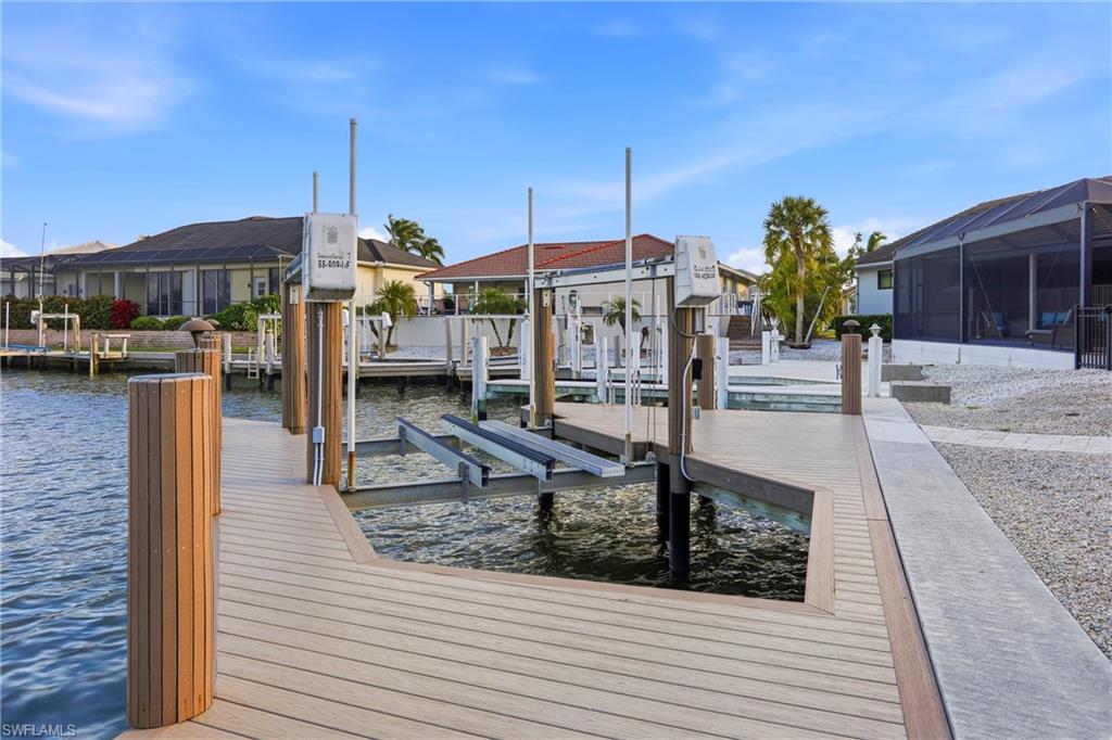 Dock area featuring a water view, boat lift, a sunroom, and glass enclosure