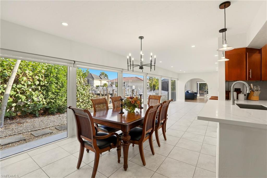 Dining space with light tile patterned floors, recessed lighting, arched walkways, and a chandelier