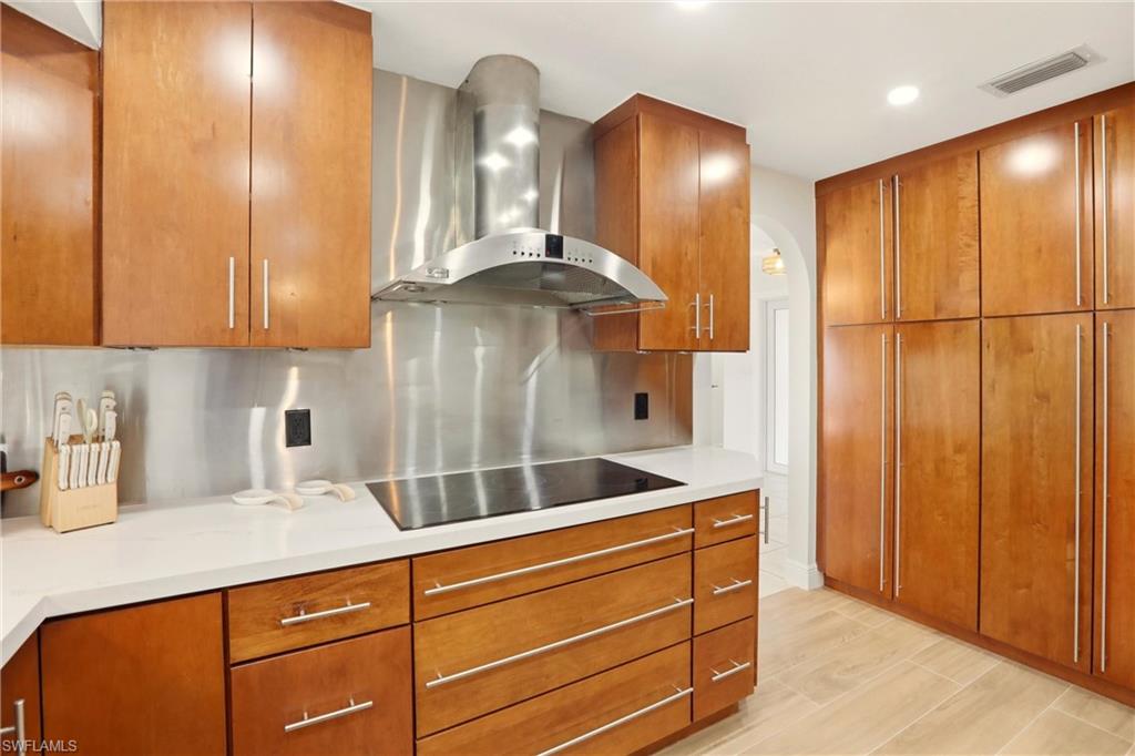 Kitchen with wall chimney range hood and brown cabinetry