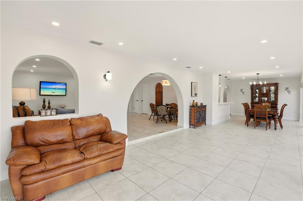 Living room featuring recessed lighting, light tile patterned flooring, and arched walkways