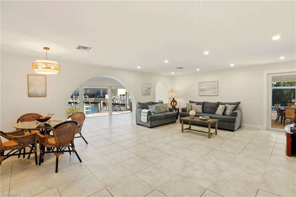 Living area featuring arched walkways, healthy amount of natural light, light tile patterned floors, and recessed lighting