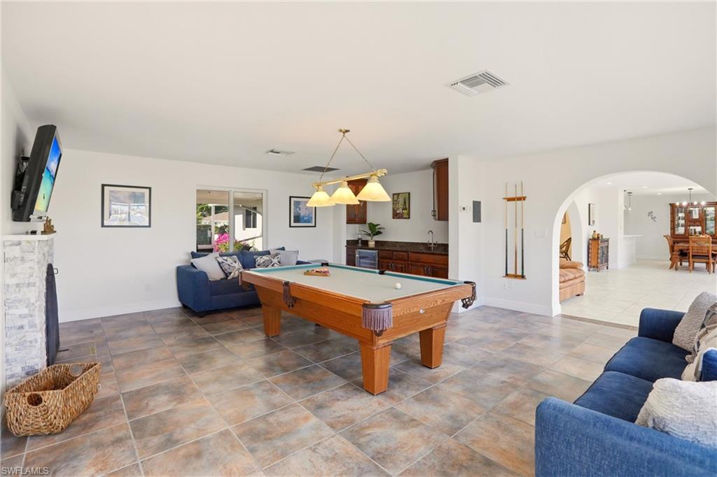 Recreation room with pool table, arched walkways, a fireplace, and wine cooler