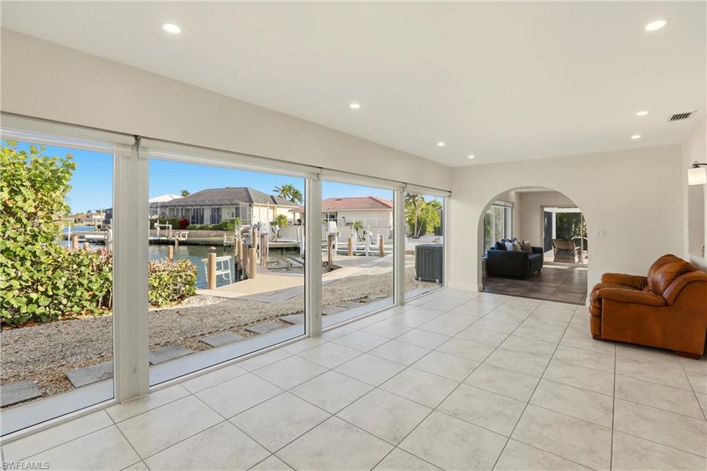 Living room featuring a water view, arched walkways, light tile patterned flooring, a residential view, and recessed lighting