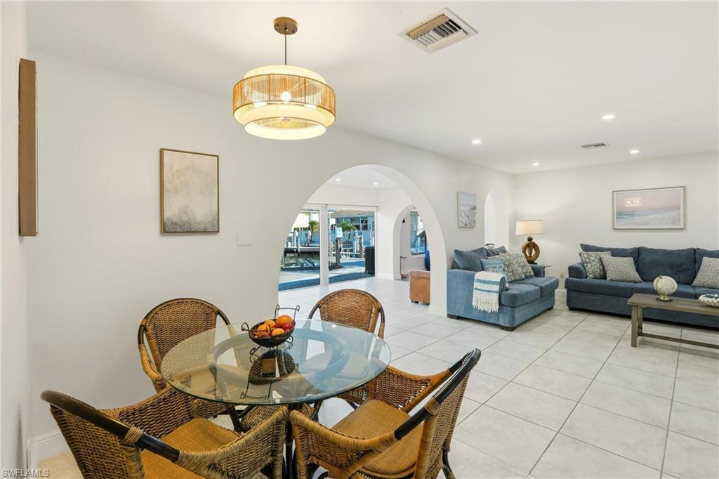 Dining space featuring arched walkways, recessed lighting, and light tile patterned floors