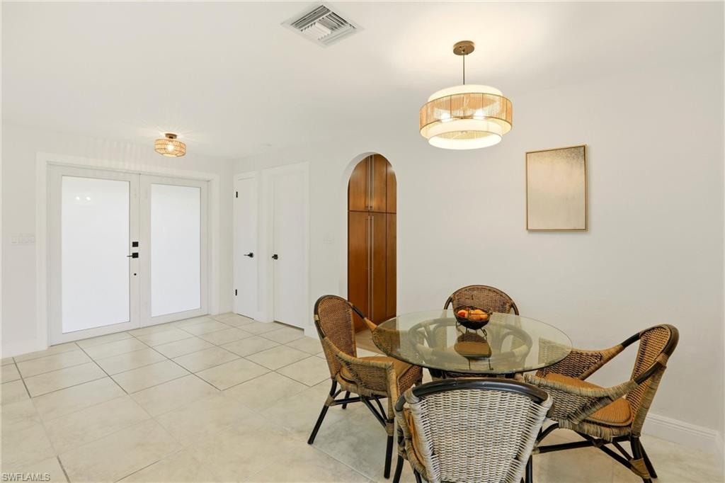 Dining space with french doors, arched walkways, and light tile patterned floors