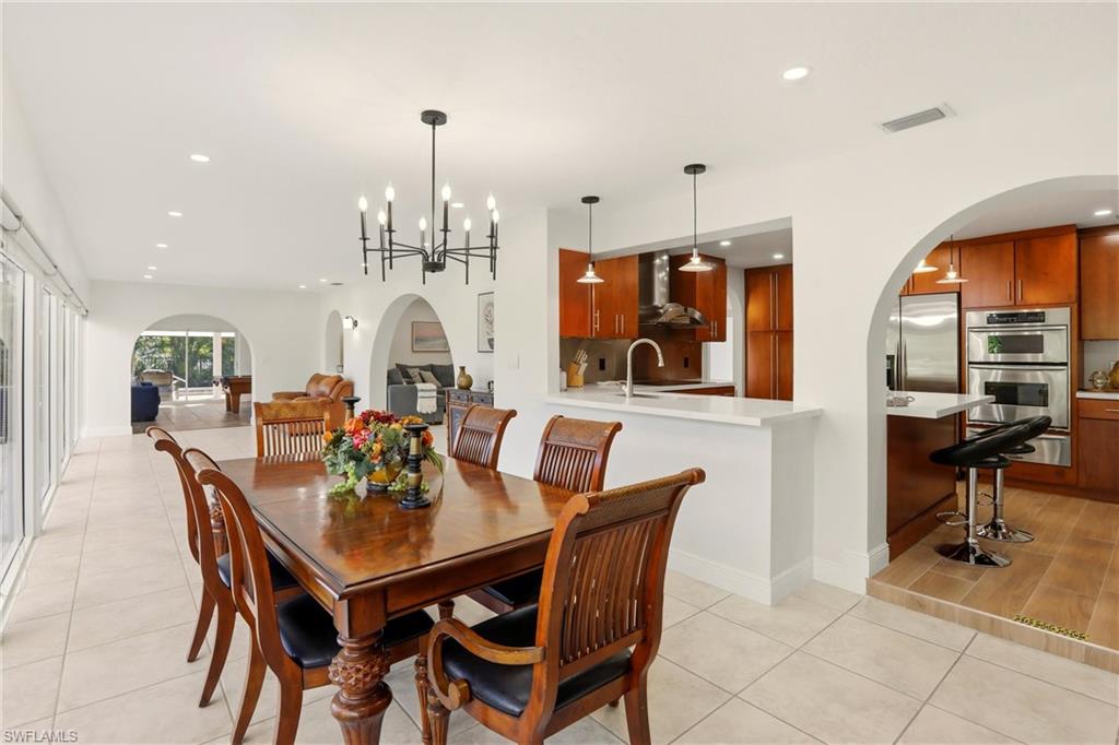 Dining room with arched walkways, recessed lighting, a chandelier, and light tile patterned floors