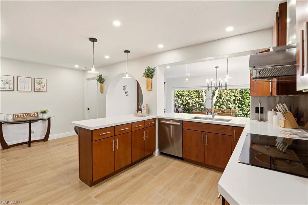 Kitchen featuring a peninsula, decorative light fixtures, brown cabinets, wood tiled floors, and recessed lighting