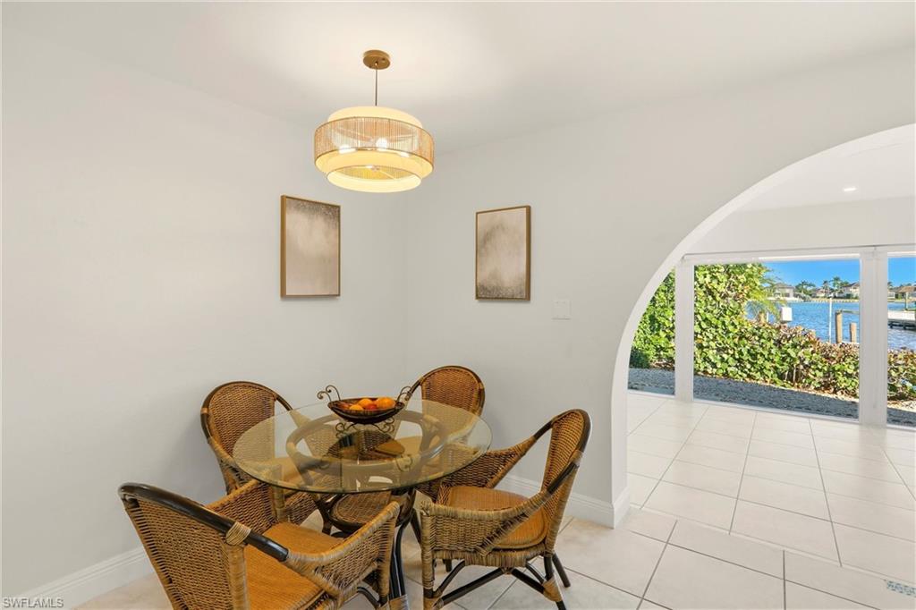 Dining room featuring light tile patterned floors, a water view, and arched walkways