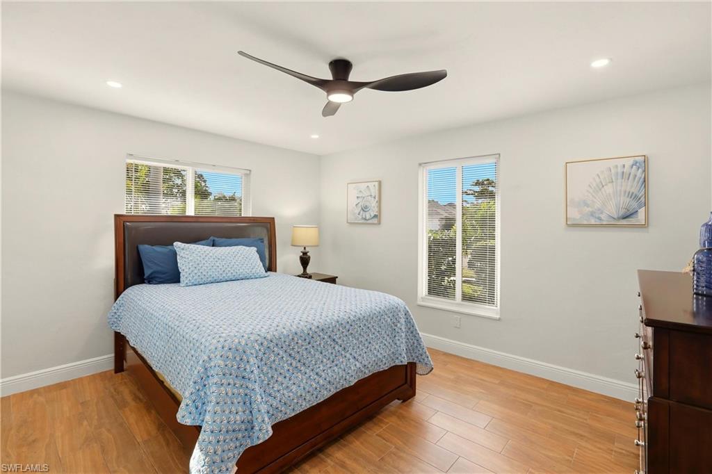 Bedroom with light wood-style floors, multiple windows, ceiling fan, and recessed lighting