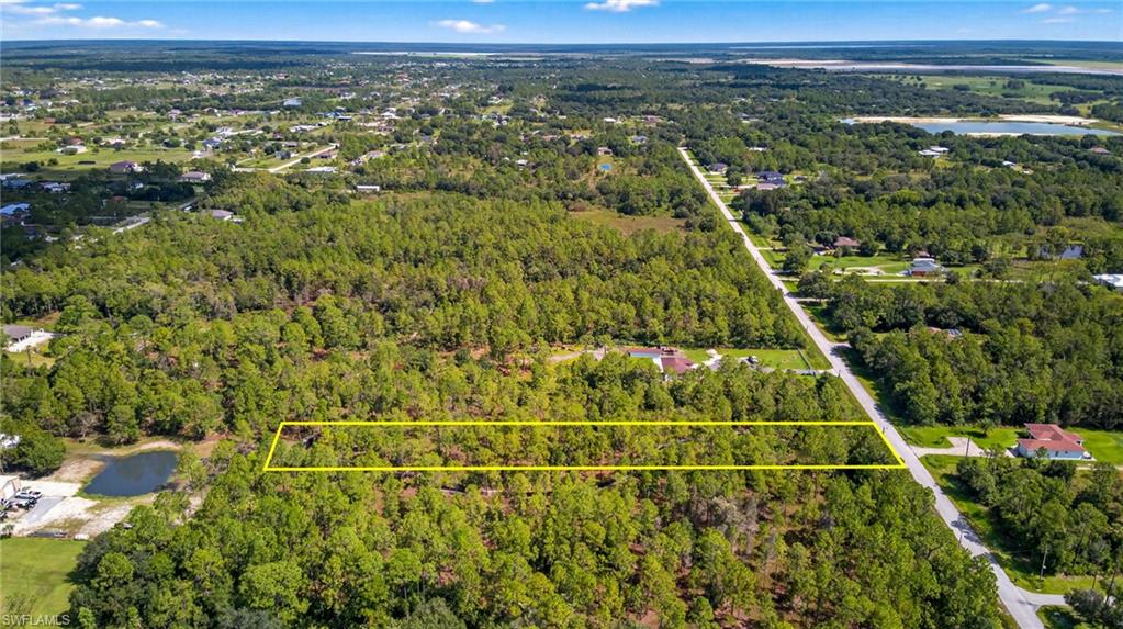 Aerial view of property and surrounding area with a nearby body of water and property parcel outlined