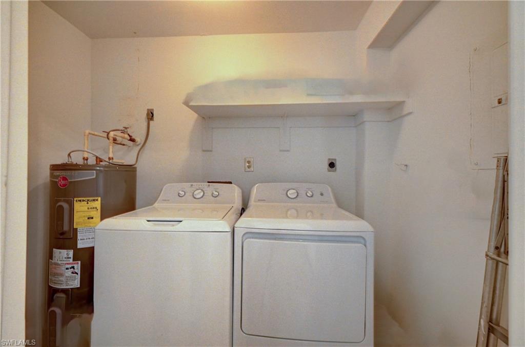 Dedicated laundry room featuring side-by-side washer and dryer with overhead cabinetry and shelving for storage, complemented by neutral finishes and recessed lighting