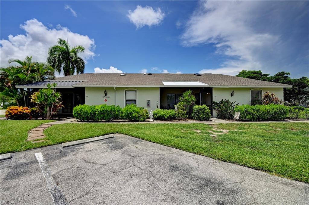Stucco exterior with a shingle roof, surrounded by mature landscaping and a manicured lawn