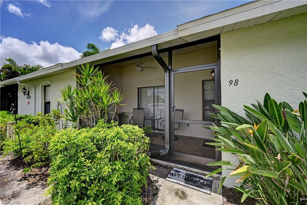 Unit 98 features a covered entry porch with black-framed glass door and sidelights, cream exterior walls, and a sloped roof with extended eaves