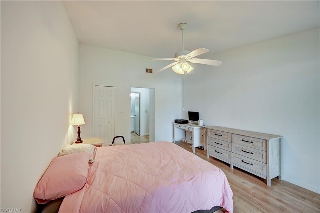 Vaulted ceiling with a ceiling fan, wood-finish flooring, and a paneled bifold door