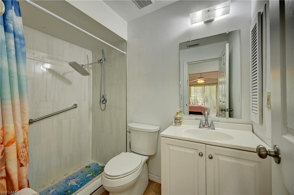 White vanity with a single basin sink, chrome faucet, and overhead lighting fixture