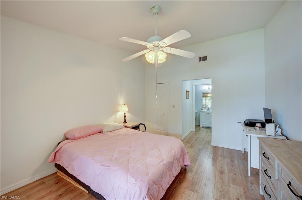 Sloped ceilings with a ceiling fan, wood-finish flooring, and white walls