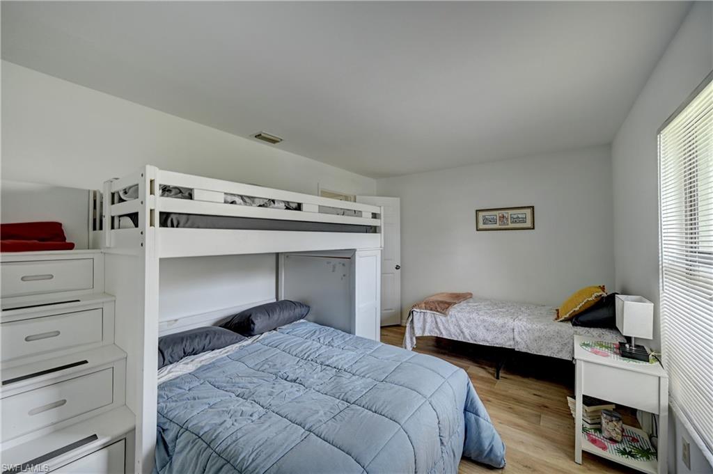 Bright interior room featuring wood-finish flooring, a white bunk bed with integrated storage drawers, and white walls