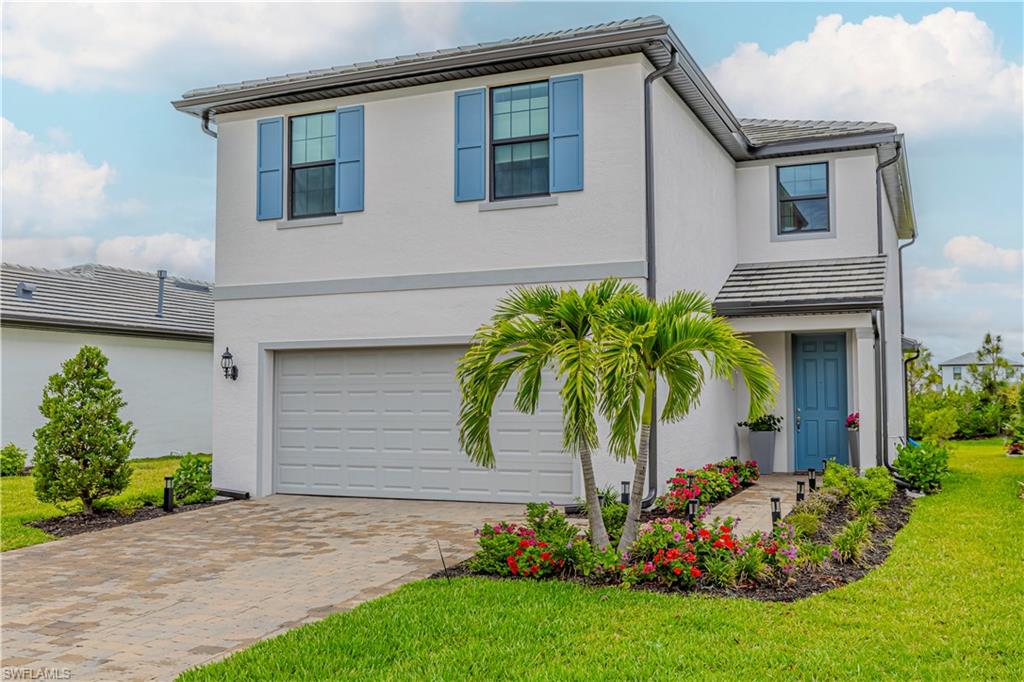 View of front of home with an attached garage, decorative driveway, stucco siding, a front lawn, and a tile roof