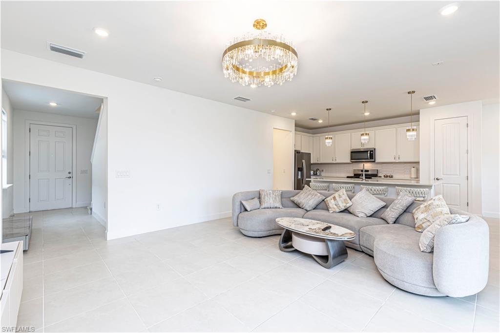 Living room featuring light tile patterned floors, a chandelier, recessed lighting, and baseboards