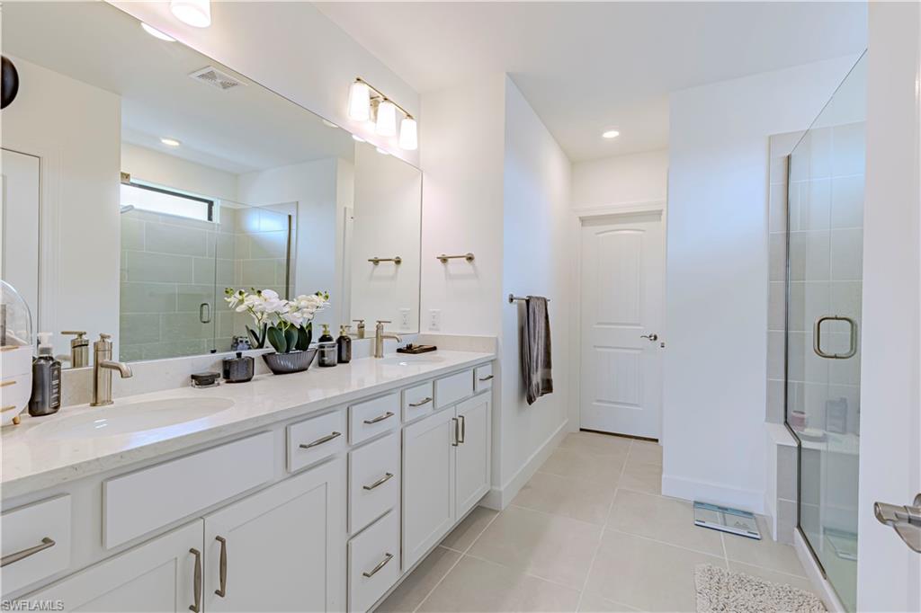 Full bath with tile patterned floors, a stall shower, and double vanity