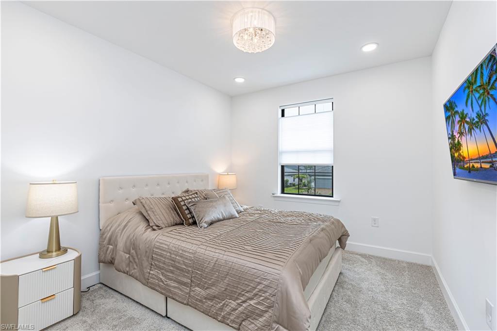 Carpeted bedroom with baseboards, recessed lighting, and a chandelier