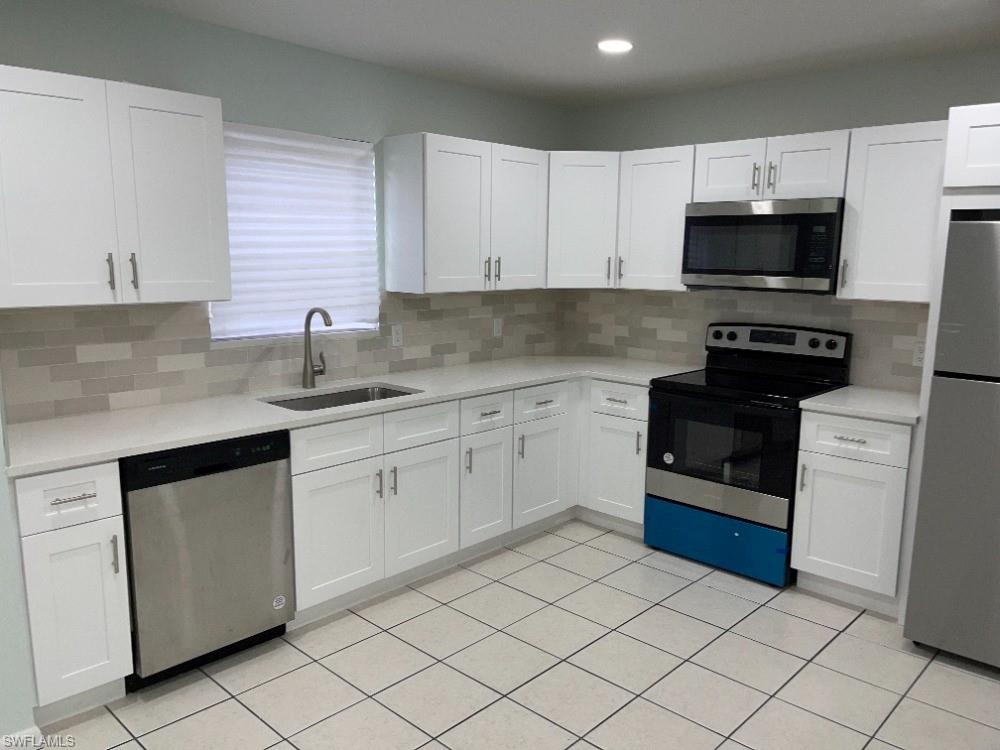 Modern kitchen featuring white shaker cabinetry, stainless steel appliances, light-toned countertops, a subway tile backsplash, and tile flooring