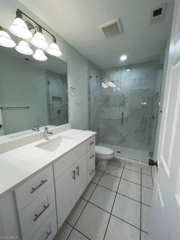 Bathroom featuring a white shaker-style vanity with a single undermount sink, a large wall mirror, and a glass-enclosed shower with subway tile flooring and large format wall tiles
