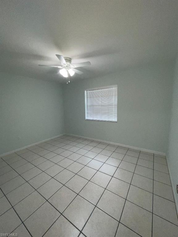 Neutral tone wall paint, a ceiling fan with integrated lighting, window with horizontal blinds, and square tile flooring