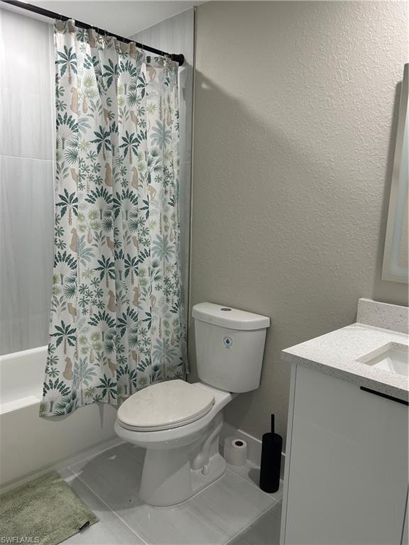 Bathroom featuring a white bathtub, light-toned wall tile surround, white toilet, and a white vanity with a light speckled countertop